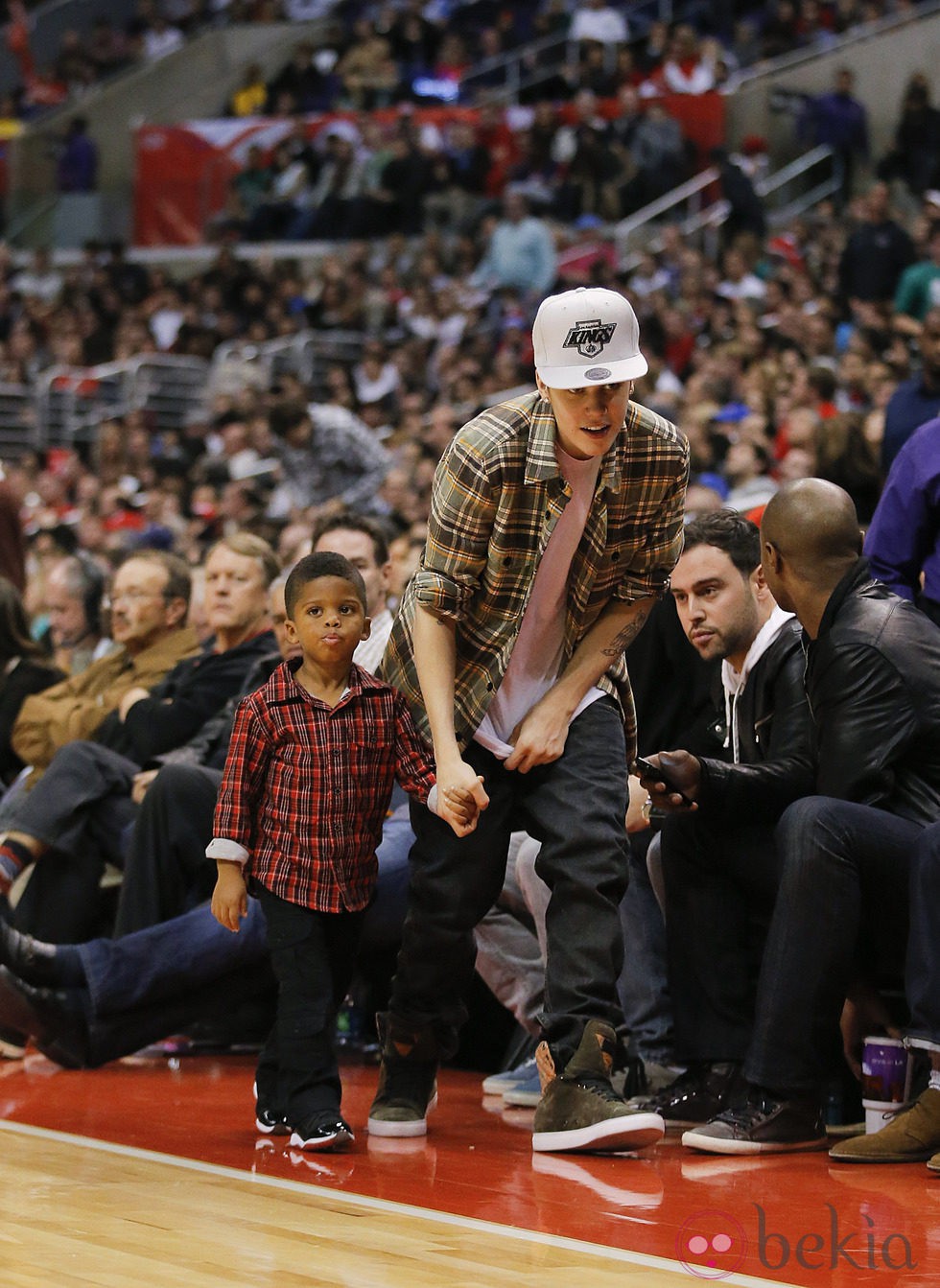 Justin Bieber con un niño de la mano en la NBA