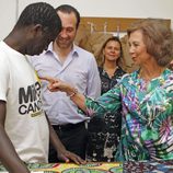 La Reina Sofía toca la camiseta de un miembro del proyecto 'koluté' de Cáritas Mallorca