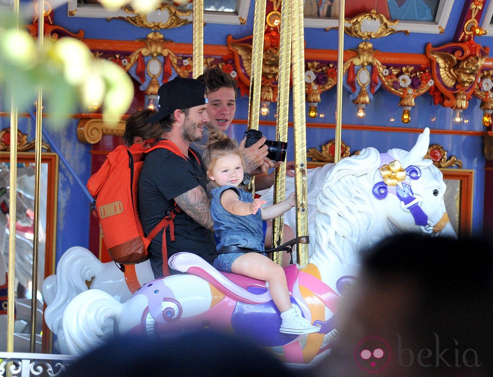 David Beckham con sus hijos Brooklyn y Harper Seven en los caballitos de Disneyland