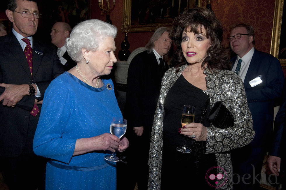 La Reina Isabel charla con Joan Collins en una recepción en Buckingham Palace