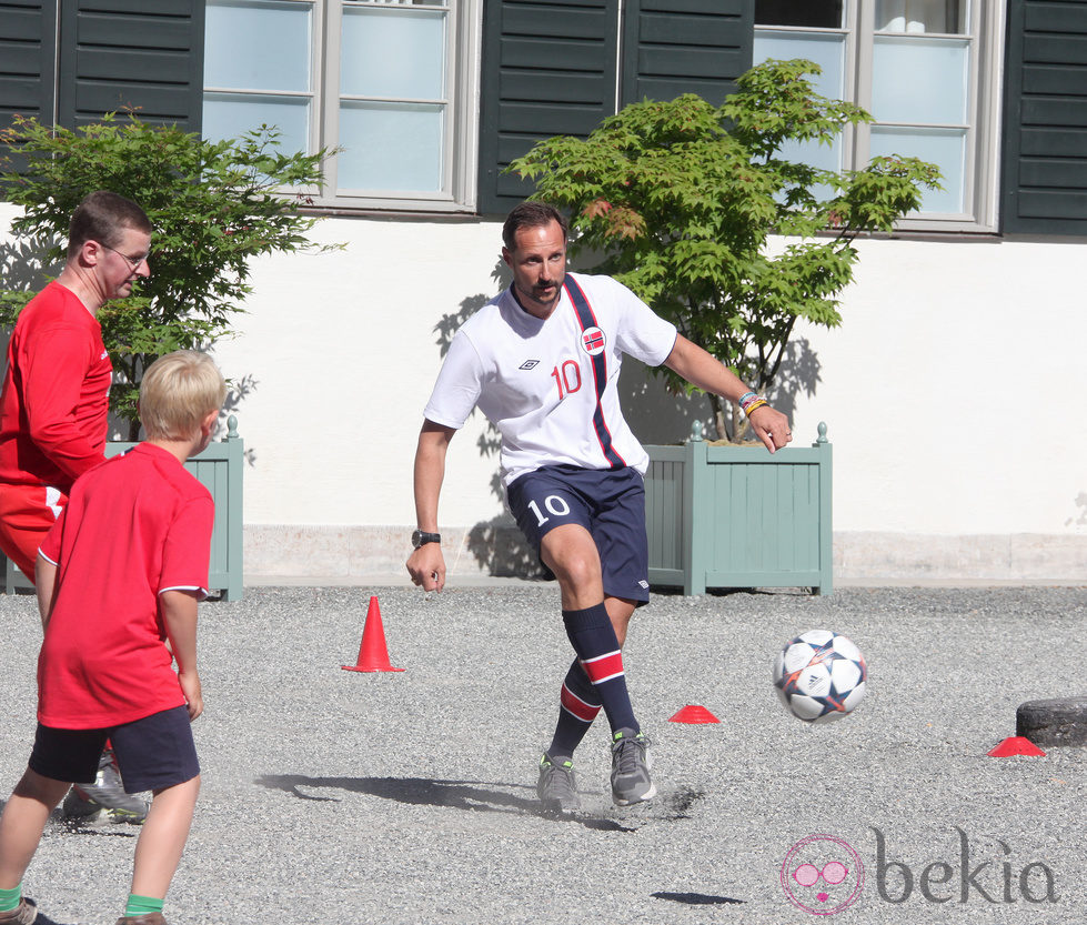 Haakon de Noruega jugando al fútbol en un partido amistoso