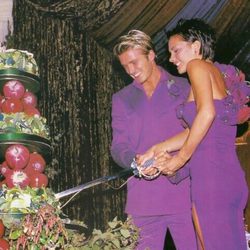Victoria y David Beckham partiendo la tarta en su boda