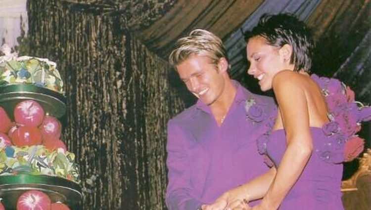 Victoria y David Beckham partiendo la tarta en su boda