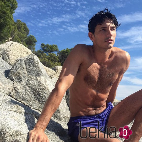 Andrés Velencoso con el torso desnudo sobre una roca