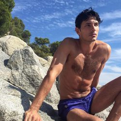 Andrés Velencoso con el torso desnudo sobre una roca