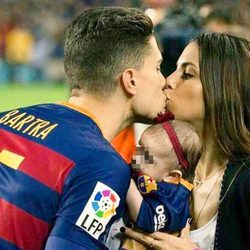 Marc Bartra y Melissa Jiménez se dan un beso junto a su hija Gala en el Camp Nou