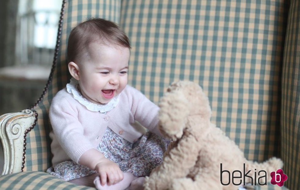 La Princesa Carlota de Cambrigde muy sonriente jugando con un oso de peluche