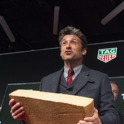 Patrick Dempsey en el Salón Internacional del Automóvil de Ginebra cargando con medio queso