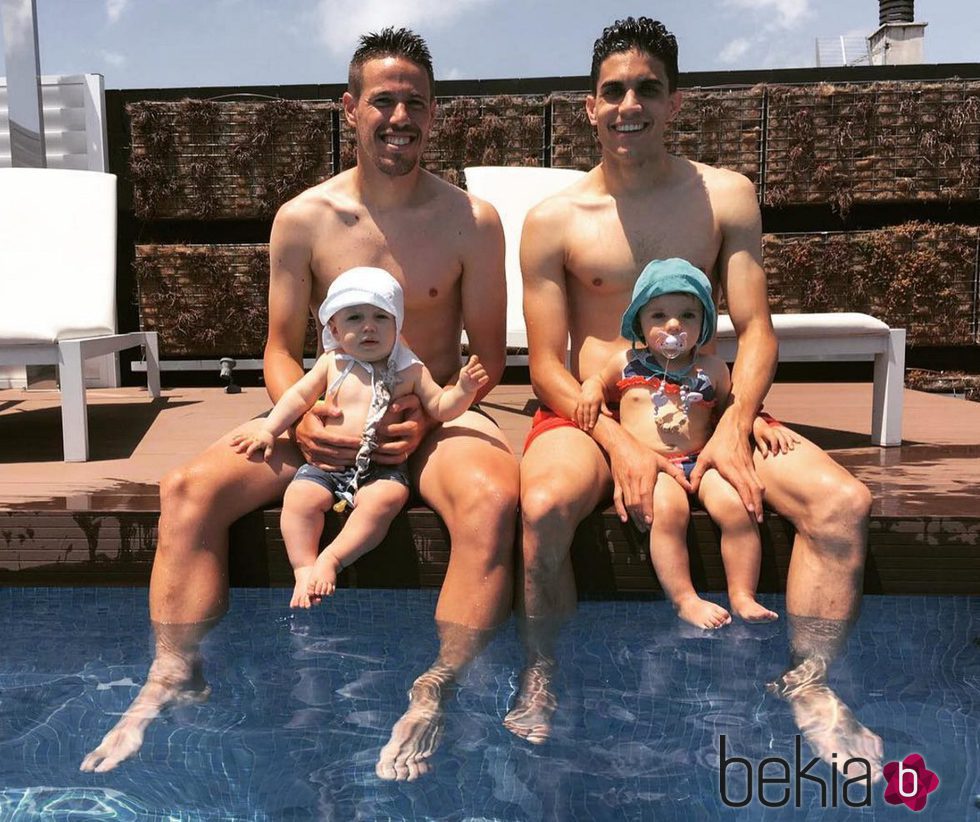 Manu Hervás con su hijo Lars y Marc Bartra con su hija Gala en la piscina
