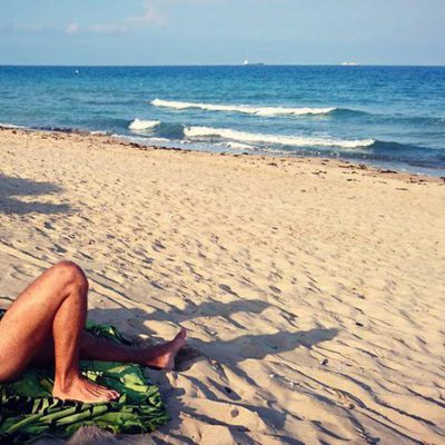 Maxi Iglesias posando desnudo tomando el sol en la playa.